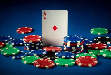 Kırmızı, mavi, yeşil ve siyah renkli poker çipleri Karo Ası 'nın etrafını sarar ve kumarhanede heyecan verici bir oyun gecesi için cazip bir ortam yaratır..