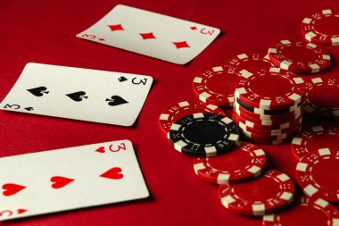 Üç kişilik bir grup veya oyun kartları ve poker fişleri kırmızı bir masaya yerleştiriliyor ve arkadaşça bir oyun akşamı boyunca heyecan ortamı yaratıyor. Pokerde güzel ve hoş bir galibiyet..