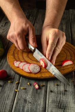 Elleri turpları ustalıkla ince mermilere böler. Kırsal kesme tahtasındaki keskin bir bıçakla. Mutfak ortamındaki hassas ve taze malzemelerin altını çizer..