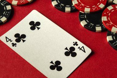 Çeşitli poker fişleri ile birlikte kırmızı keçeli kalemlere dört kart konur. Mekan, rekabetçi bir poker oyunu sırasında heyecan verici bir kumarhane atmosferi olduğunu gösteriyor..