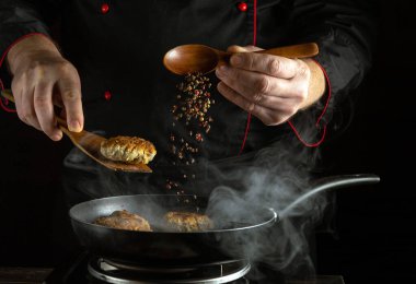 Yetenekli bir şef bir tavada köfte pişirirken bir de baharat karışımı ekliyor. Buhar yükseliyor ve bir restoranın mutfağındaki bu mutfak deneyimi atmosfere karışıyor..