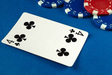Sinek kartlarından dördü, çeşitli renklerde poker fişleri ile çevrili mavi bir masanın üzerinde duruyor. Bu da yoğun bir kumar ortamı ve rekabetçi bir ruh olduğunu gösteriyor..
