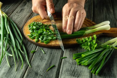 Eller ustalıkla taze soğan ve kişniş doğruyor. Köy mutfağında doğal ahşap dokular ve canlı yeşiller sergileniyor..