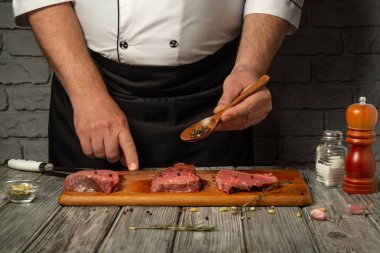Yetenekli bir şef ahşap bir kaşıkla üç dilim çiğ eti tatlandırıyor. Mutfağın, taş duvarları ve yemek pişirme aletleri olan samimi bir havası var..