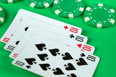 Yeşil çipler ve dördünün kombinasyonu olan iskambil kağıtları bir kulüpteki poker masasında rastgele serilirler. Başarılı bir galibiyet kavramı.