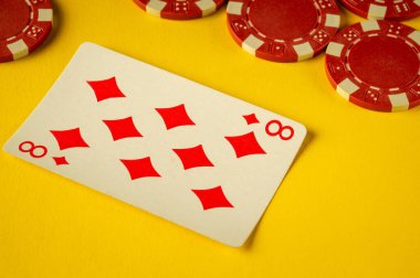 Parlak sarı arka planda kırmızı poker çiplerinin yanında karo sekizincisini gösteren bir kart var. Heyecan verici bir poker oyunu için zemin hazırlıyor..