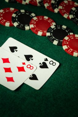 İki iskambil kağıdı, bir kupa sekizlisi ve bir maça sekizlisi, kırmızı ve siyah poker fişleri etrafa saçılmış yeşil keçeli bir yüzeye uzanıyorlar. Atmosfer arkadaşlarla sıradan bir oyun gecesini akla getiriyor..