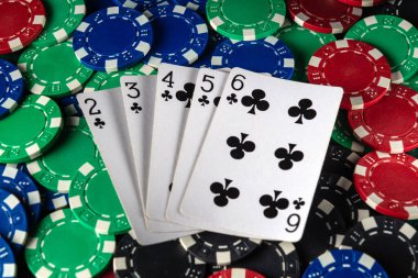 Sifon kombinasyonlu beş kart renkli kumarhane fişleri üzerine serilmiş, akşam saatlerinde evde arkadaşça poker oynamak için rahat bir ortam yaratıyor..