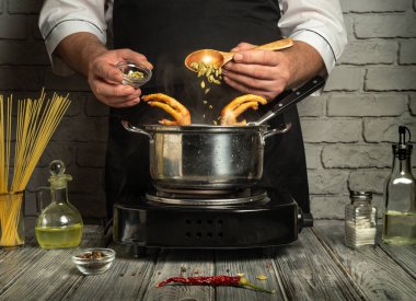 Becerikli bir aşçı, taze malzemeler ve mutfak aletleriyle çevrili bir tencereye ustalıkla baharat ve deniz ürünleri ekler. Kırsal mutfağın büyüleyici bir atmosferi var..