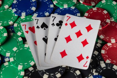 Parlak renkli poker fişleri, dört yedili bir oyun gecesinin heyecanını arkadaşlarıyla paylaşan kazanan kartların etrafını sarar..