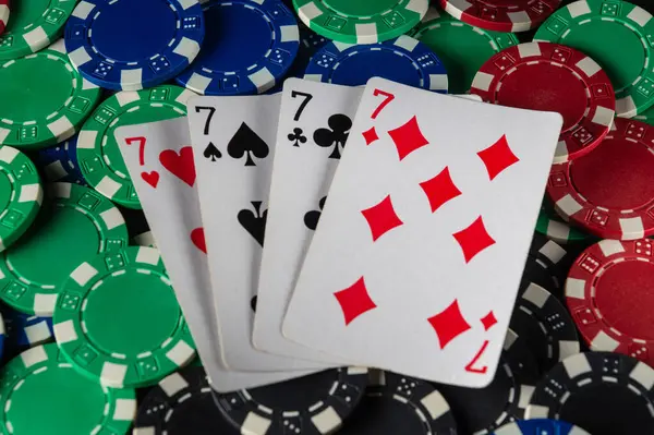 Parlak renkli poker fişleri, dört yedili bir oyun gecesinin heyecanını arkadaşlarıyla paylaşan kazanan kartların etrafını sarar..