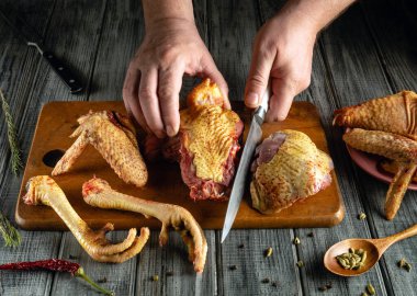 Doğal ışıkla dolu rahat bir mutfakta baharat ve otlarla çevrili ahşap bir tahtanın üzerinde ustalıkla kesilmiş çiğ kümes hayvanları..