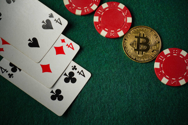 On a green felt surface are three of a kind or set playing cards and red poker chips, as well as a Bitcoin coin, indicating a poker game that combines traditional and digital currencies.