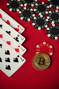 Four of a kind or quads playing cards are laid out next to black and red poker chips. A shiny Bitcoin coin lies nearby, evoking the atmosphere of modern gambling.