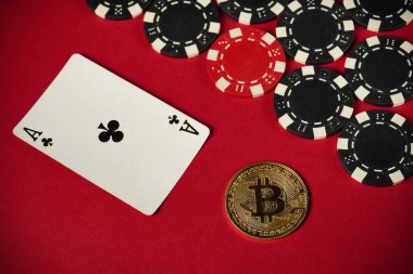 A game scene shows an ace of clubs card next to a bitcoin coin and various poker chips on a vibrant red surface. This setup suggests a mix of traditional and digital gambling.