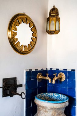 Traditional wash basin and golden mirror and lamp in the corner of the  riad's bedroom, Medina of Fez, Morocco, North Africa