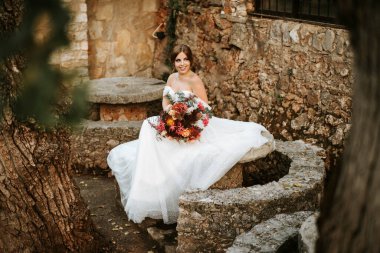 Taş bahçesinde buketi olan güzel bir gelin.