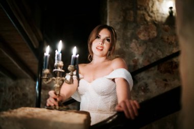 Güzel gelinin portresi, gecenin bir yarısı eski taşralı bir iç mekanda mum tutuyor.