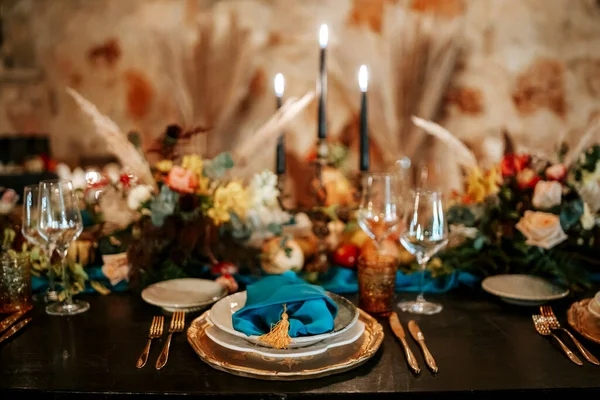 Exquisite, elegant golden and blue table set decoration in moody dark colors
