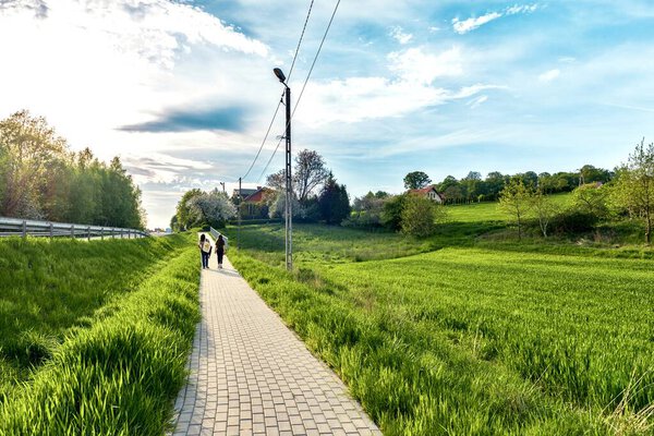 Couple walking on a road in the village. Spring landscape Poland.