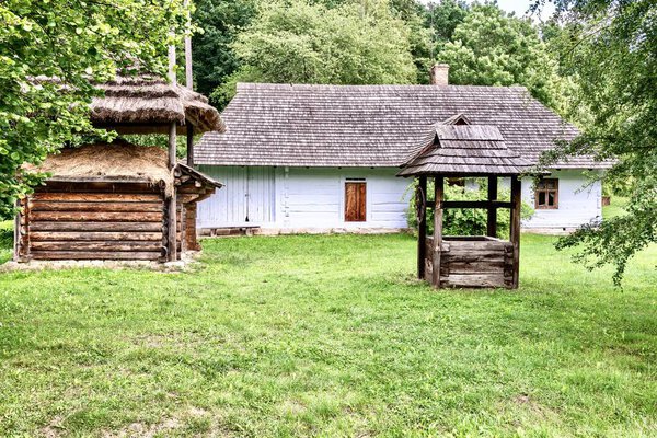 Вид на древний деревянный колодец, сено и другие постройки в польской деревне Санок, Польша.