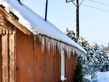 Buz saçakları kışın evin çatısından sarkıyor..