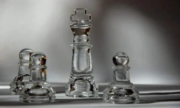 King and Pawns - Glass Chess Pieces in Formation - Closeup, Light and Shadow