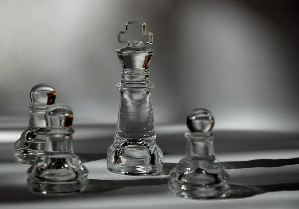 King and Pawns - Glass Chess Pieces in Formation - Closeup, Light and Shadow