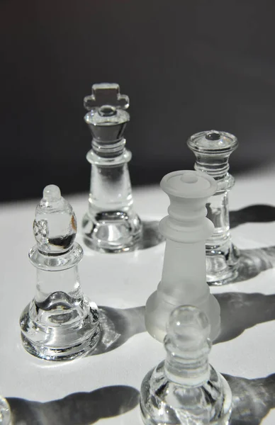 King, Queen, Bishop, Knight, Rook and Pawns - Glass Chess Pieces in Formation - Closeup, Light and Shadow