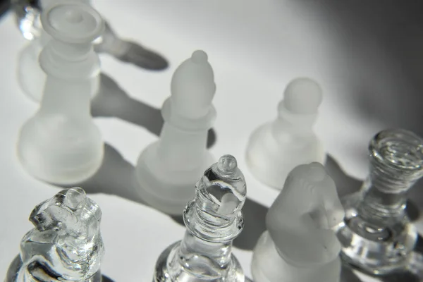 King, Queen, Bishop, Knight, Rook and Pawns - Glass Chess Pieces in Formation - Closeup, Light and Shadow