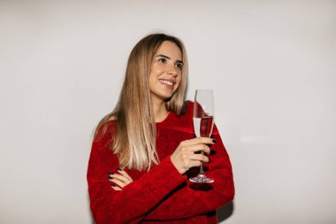 Gülümseyen, güzel gülüşü olan ve elinde bir bardak şarapla mutlu, gerçek duygularıyla yan yana bakan çekici sarışın kadın. Kırmızı gömlekli güzel bir kızın kapalı arka planda poz verirken çekilmiş kapalı bir fotoğrafı. 