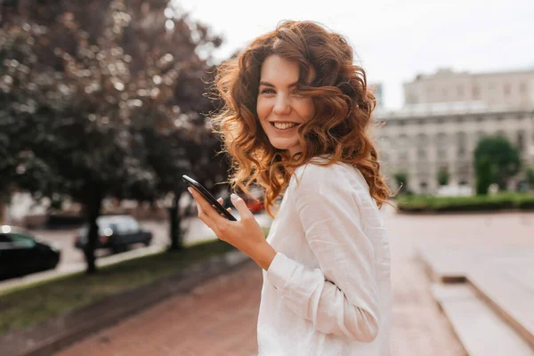 Зображення Усміхненої Європейської Жінки Хвилястим Рудим Волоссям Тримає Телефон Дивиться — стокове фото