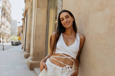 Arka planda duran güzel esmerin dışarıda çekilmiş fotoğrafı. Mutlu bir gülümsemeyle eski şehir caddesinde. Beyaz tenli gülücükler ve kameraya bakın.