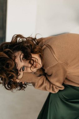 Photoshoot sırasında kameraya poz veren kıvırcık saçlı güzel bir kadının kapalı bir portresi. Beyaz arka planda oynaşan güzel kıvırcık kızın stüdyo fotoğrafı.. 