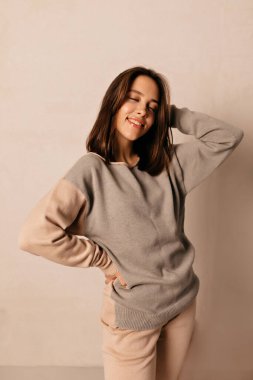 Koyu renk saçlı, güzel bir kız ve mutlu bir gülümsemeyle izole edilmiş arka planda beyaz fotoşoplar çiziyor. O örgü bej takım elbise giyiyor.