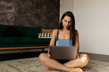 Stylish young smiling woman in home casual clothes sitting at home with laptop and typing with smile. Confident woman expert with happy smile with teeth. 