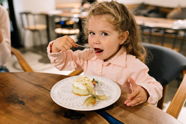 Charming Cute Little Girl Curly Hair Wearing Pink Shirt Eating Stockfoto