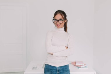 Ecstatic brunette woman with nude make-up standing over work place and enjoying music during break in office. Successful stylish freelance woman works from home