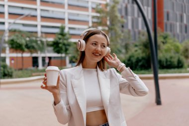Beyaz ceketli, kulaklıklı, gülümseyen Avrupalı kadını cezbetmek, elinde bir fincan kahveyle kentin caddesinde dikilmek ve müzik dinlemekten zevk almaktır.. 