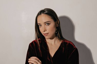 Şehvetli esmer kadın izole bir arka planda kameraya poz veriyor. Tatil makyajlı güzel Avrupalı kadının kapalı bir portresi..