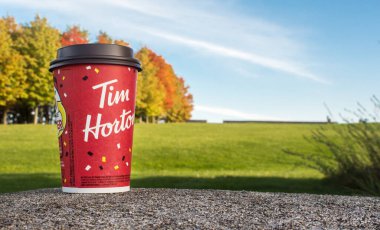 Kırmızı Kağıt Tim Hortons fincanı arka planda oyun kupası kazanan sonbahar ağaçları. Taze sabah kahvesi. Ottawa, On, Kanada - 20.10.2022.