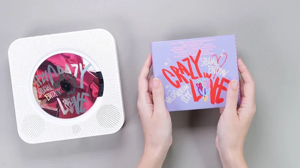 stock image Fan hands holding 1st music album of k-pop group Itzy CRAZY IN LOVE on grey background. Pink music CD in white retro player. South Korean girl group Itzy. Gatineau, QC Canada - November 10 2022.