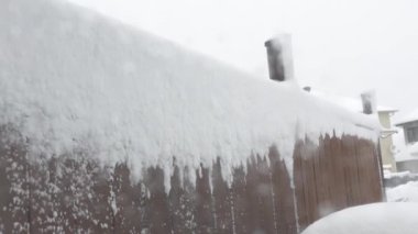 View of the fencecovered with snow in heavy snowfall with blizzard and wind gusts against the background