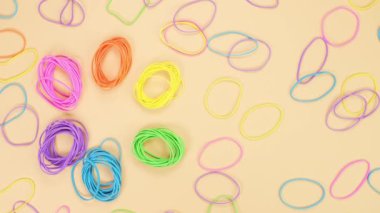 Hands broke rainbow rubber bands in shape of flower and mixed them on yellow background. Bright flower from office rubber bands. Multicolored elastic rubber bands close up