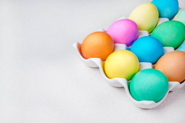 Pastel Paskalya yumurtaları beyaz masada yatıyor. Geleneksel dekorasyon