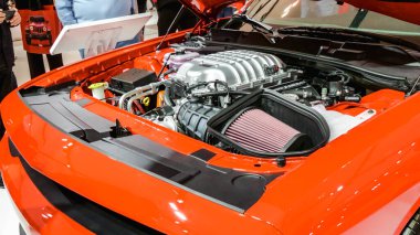 Close view of motor of red Jeep car on display. Crowds looking at new car models at Auto show. National Canadian Auto Show with many car brands. Toronto ON Canada Feb 19, 2023