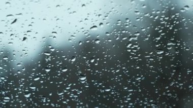 Snow fall on window and melting into water drops on glass in the forest. Large rain drops strike window during winter shower. Pure rain drops