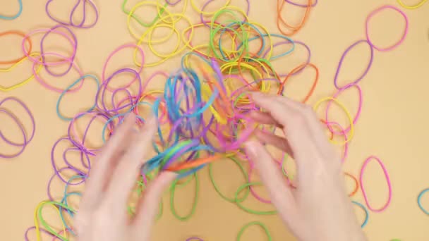 Руки Играют Кучей Разноцветных Резиновых Лент Желтом Фоне Яркие Офисные — стоковое видео