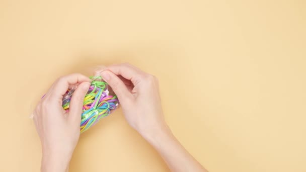 Händerna Försöker Stänga Liten Plastpåse Med Massor Färgglada Gummiband Gul — Stockvideo