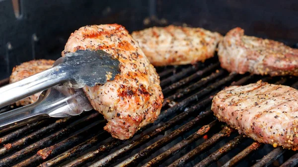 暗い背景に炎とステンレスバーベキューグリルで肉ステーキを焼きます 食と料理のコンセプト — ストック写真